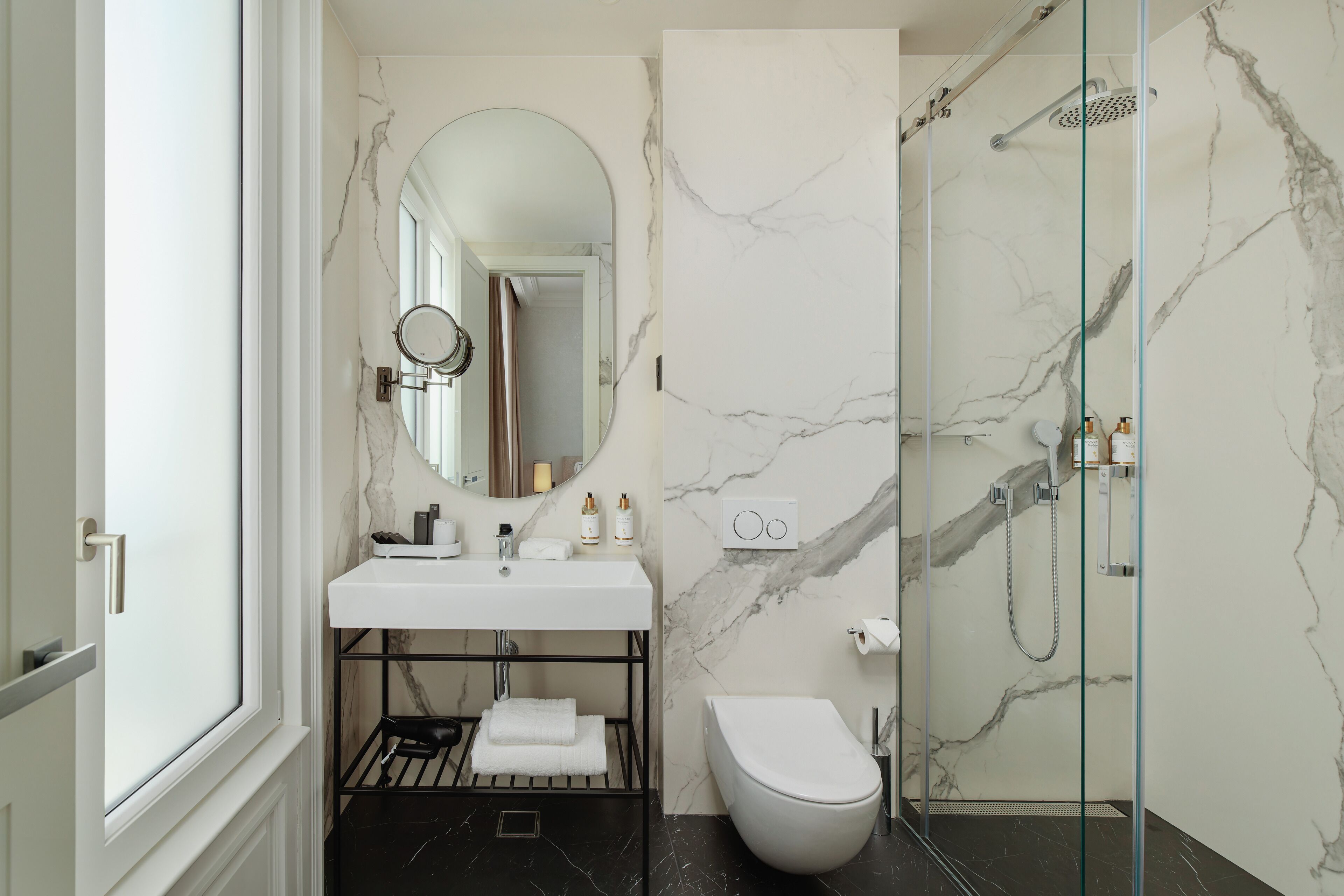 A modern bathroom with a white sink, a toilet, and a glass-enclosed shower.