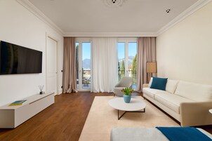 Una sala de estar moderna con un televisor de pantalla plana, un sofá, una mesa de centro y una silla.