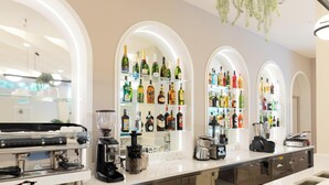 Una zona de bar con máquinas de espresso, un molinillo de café y estantes llenos de botellas de licor.