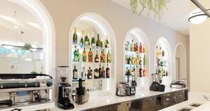 Ein moderner Barbereich mit einer Kaffeemaschine, einem Mixer und Regalen voller verschiedener Flaschen.