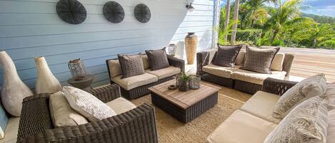A covered outdoor seating area with wicker furniture, cushions, and decorative vases.