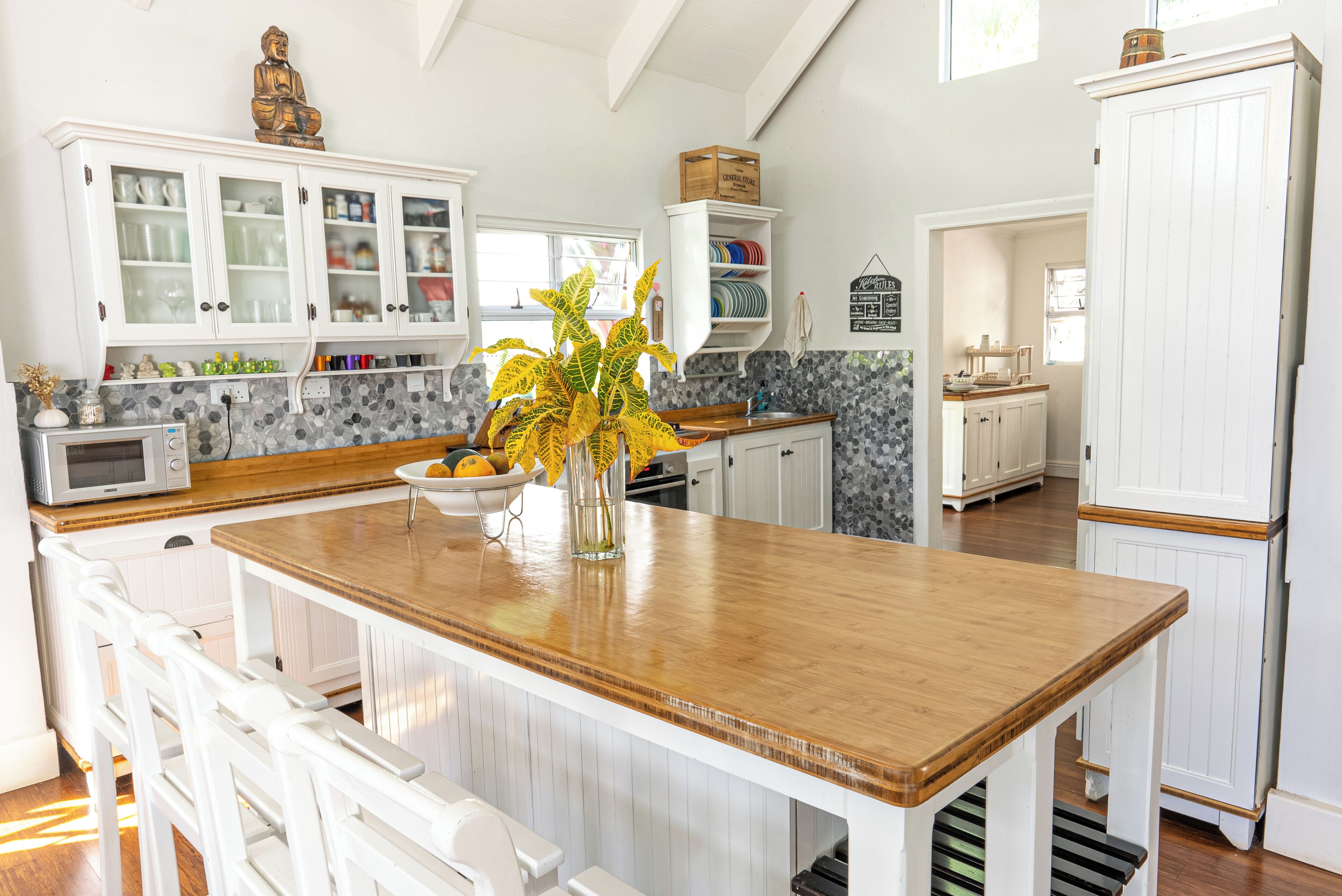 Una cocina con armarios blancos, una isla de madera y una estatua decorativa de Buda.