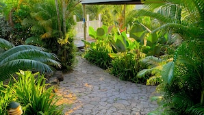 A stone pathway surrounded by lush greenery and a white fence.