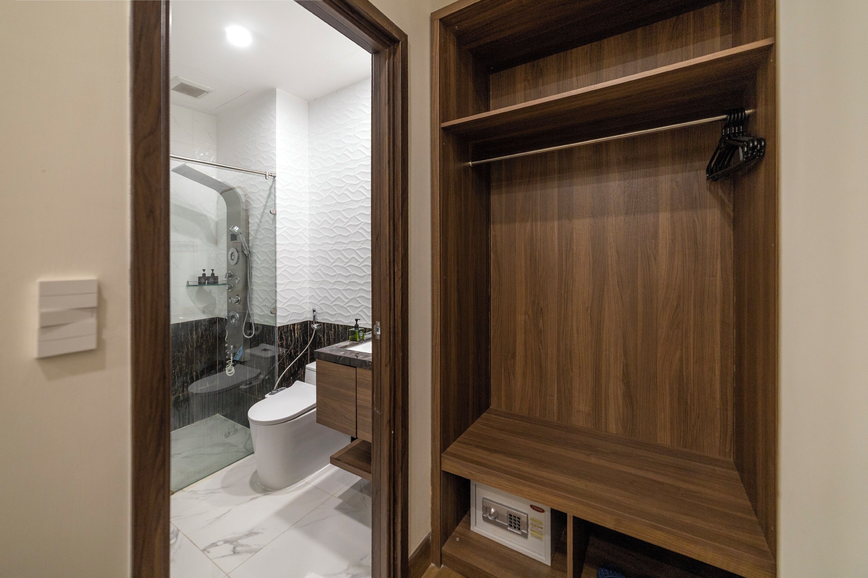 Une salle de bain moderne avec une douche à parois de verre, des toilettes blanches et des étagères en bois.