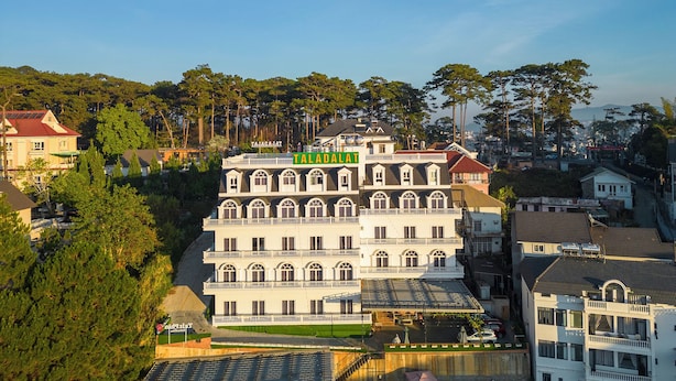 A multi-story building with a prominent sign reading "TALADALAT" and a balcony on the second floor. - Tala Dalat Hotel (Xuan Huong - Da Lat)