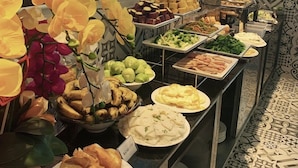 A buffet with various food items and a decorative orchid arrangement. - Tala Dalat Hotel (Xuan Huong - Da Lat)