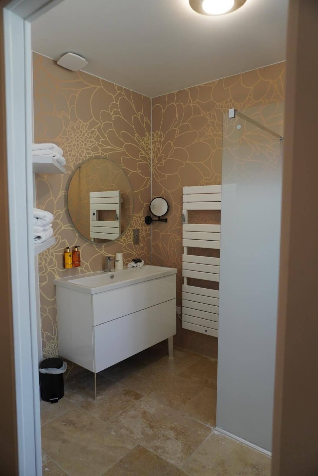 A bathroom with a white vanity, a round mirror, and a towel rack.