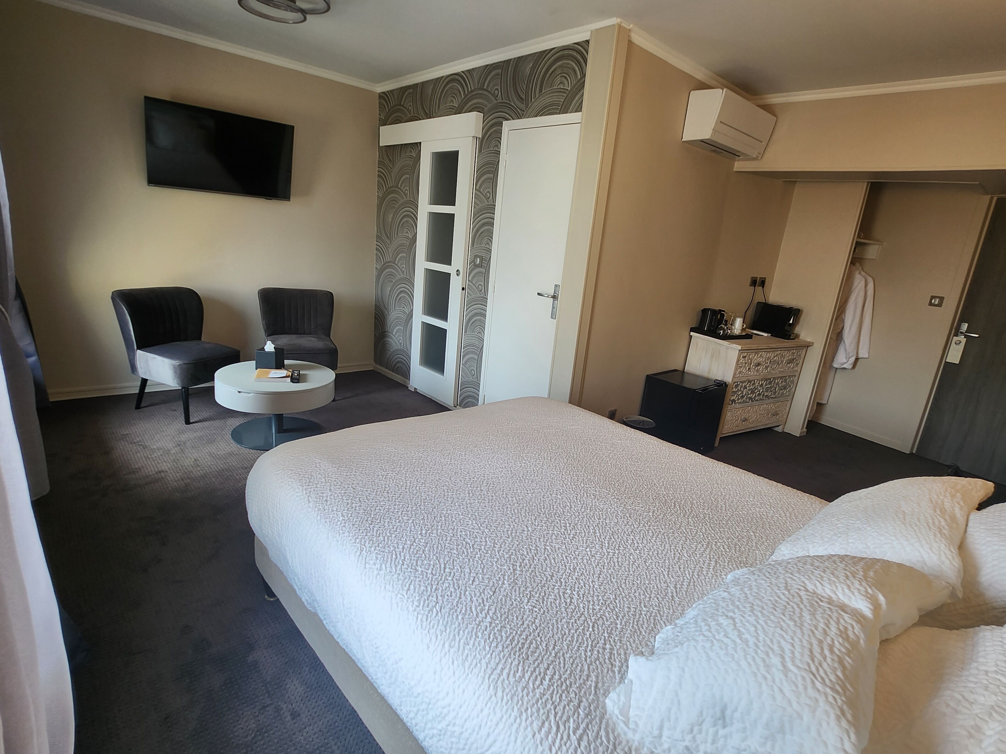 Hotellihuone, jossa on suuri sänky, työpöytä, tuoli, televisio, vaatekaappi ja kylpyhuone.