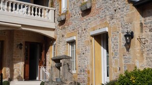 A stone building with a balcony, a stone fountain, and a brick pathway. - Hôtel Villa Pona (Digoin)