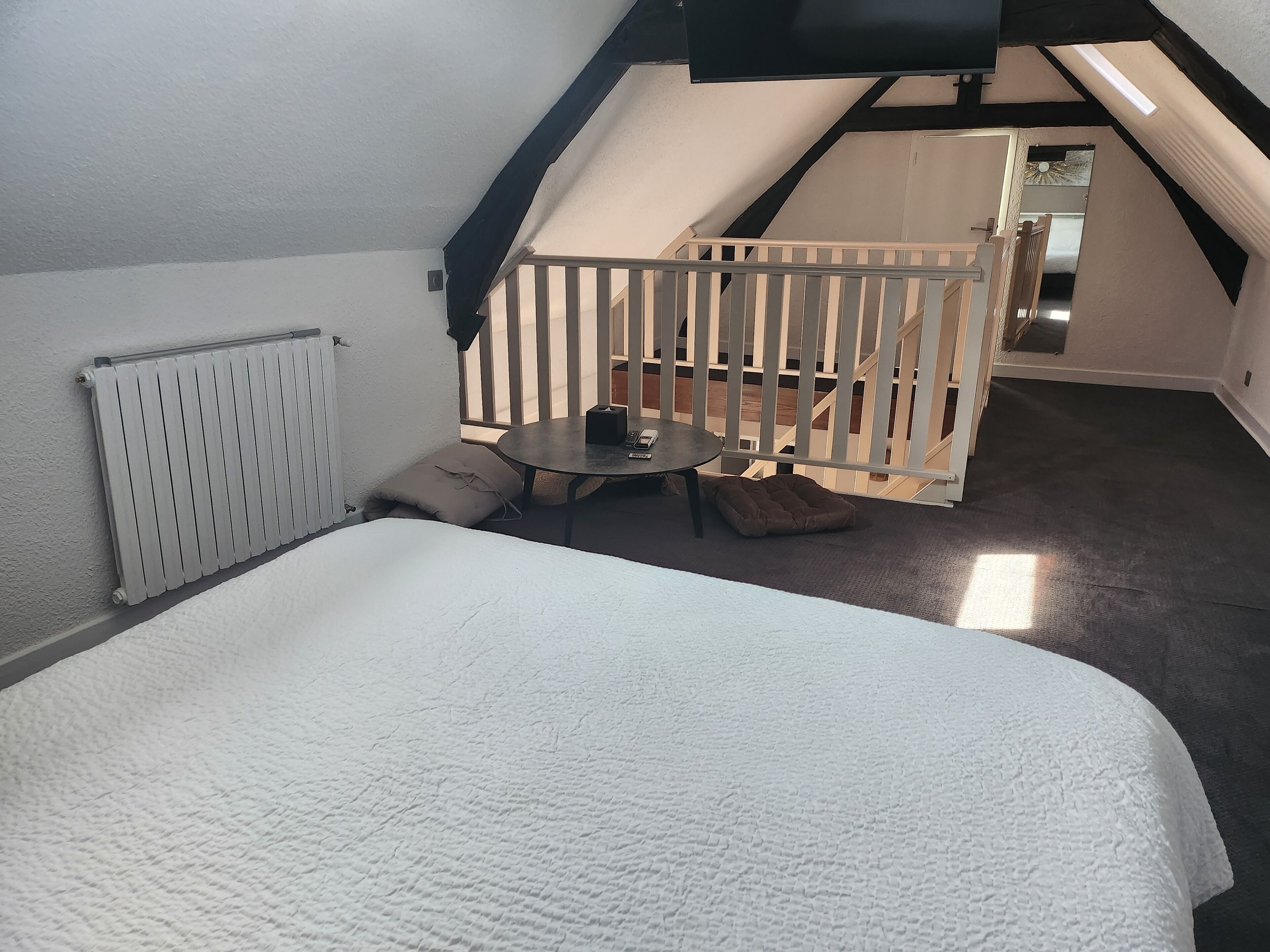 A bedroom with a large bed, a small table, and a balcony with a railing.