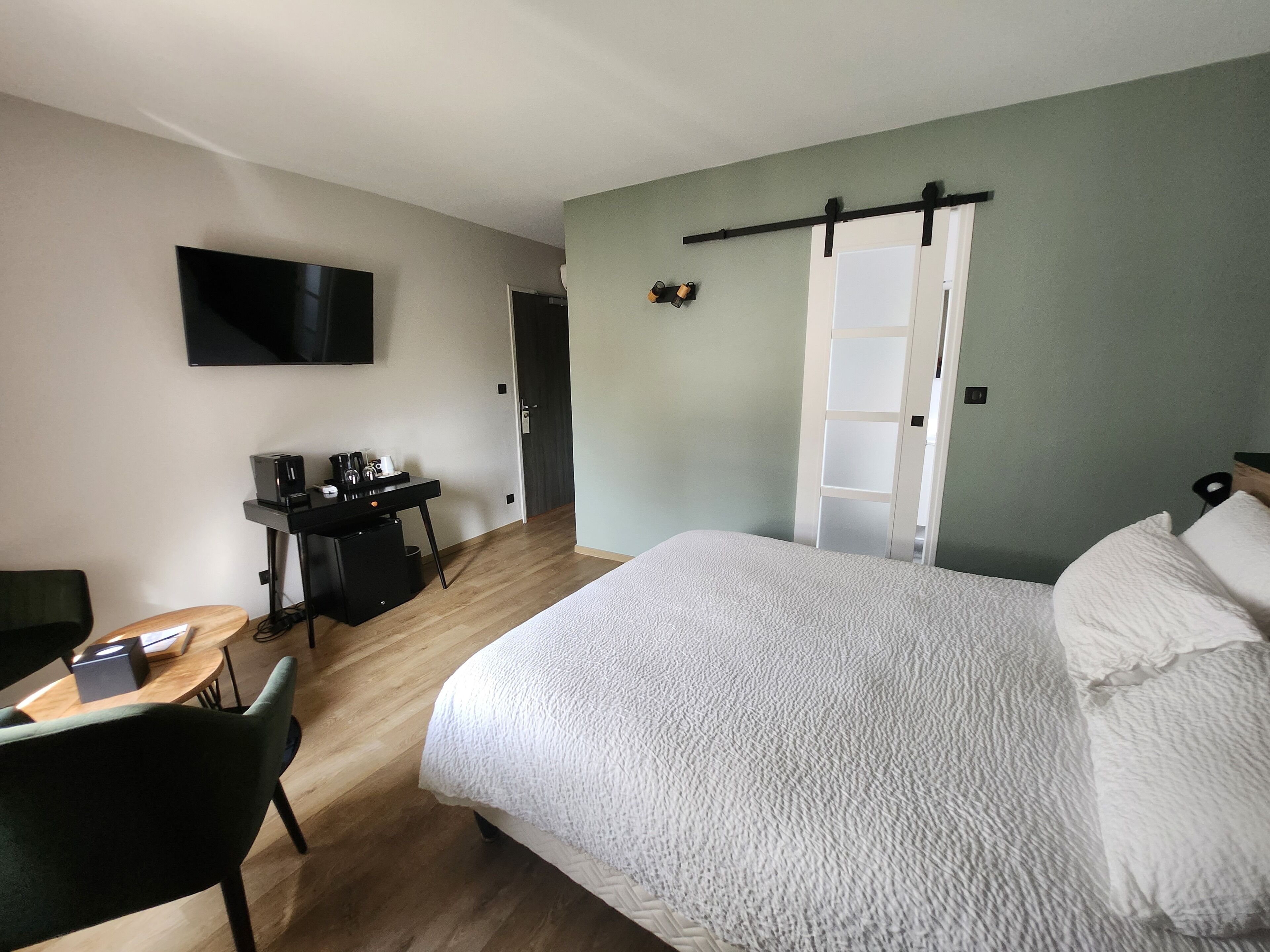 Een hotelkamer met een bed, een bureau met een computer, een stoel, een televisie en een kledingkast.