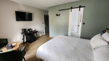 Een hotelkamer met een bed, een bureau met een computer, een stoel, een televisie en een kledingkast.