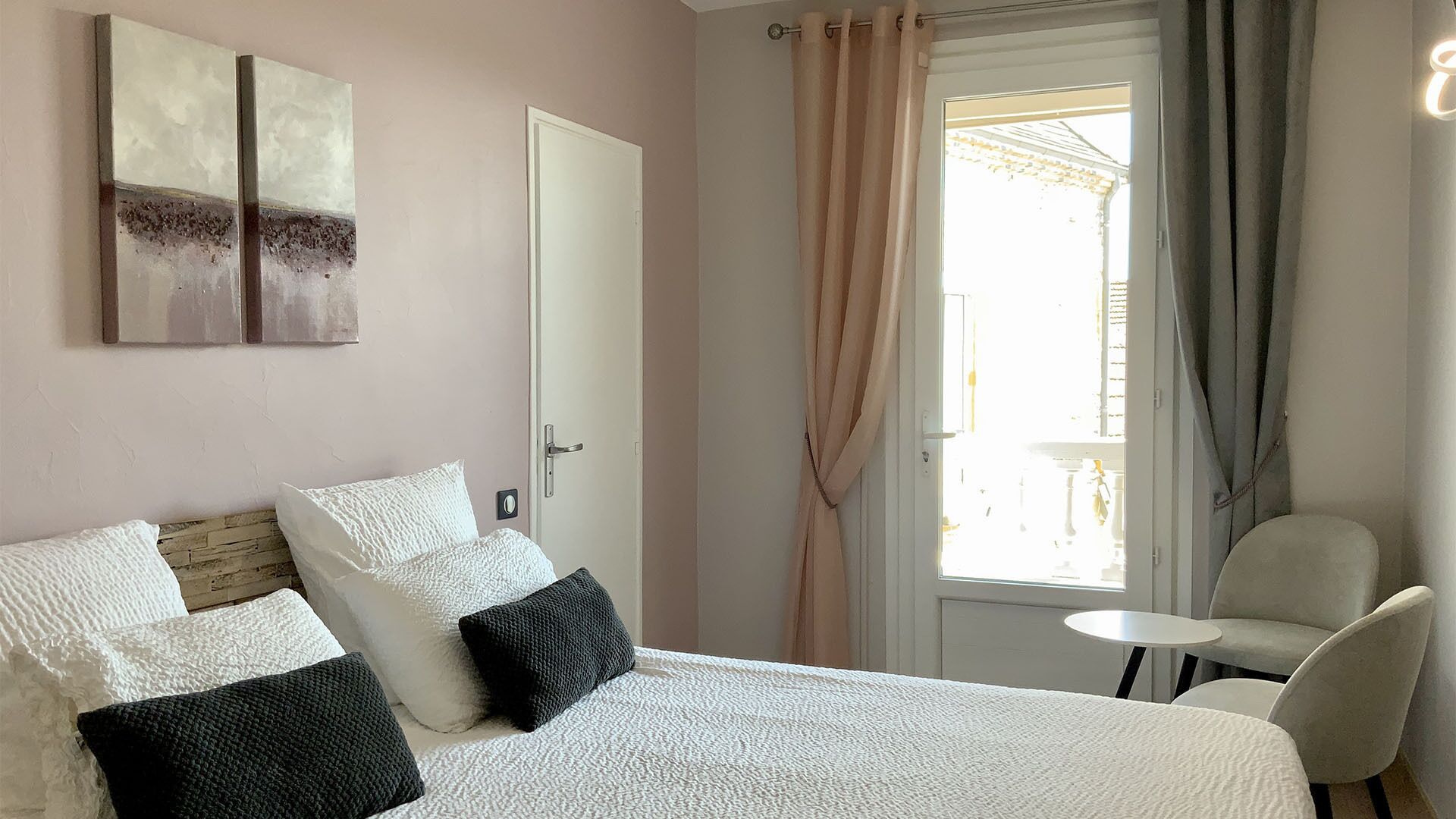 Une chambre à coucher avec un lit, une chaise, une petite table et une fenêtre avec des rideaux.