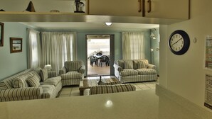 A living room with striped sofas, a coffee table, and a dining area with a table and chairs. - Top Deck Langebaan 6-sleeper (Langebaan)
