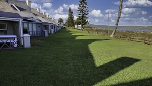 A row of modern houses with a grassy pathway leading to a beach. - Top Deck Langebaan 6-sleeper (Langebaan)