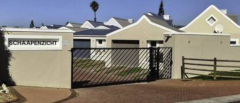 A gated residential complex with numbered units and a sign reading "SCHAAPENZICHT".