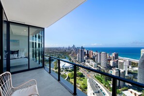 A balcony with a city view, a bed, and a chair. - Magnificent Full Ocean View at Casino Free Parking (Broadbeach)