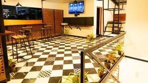 Un pavimento a scacchi, una zona con posti a sedere e uno schermo televisivo nella hall.