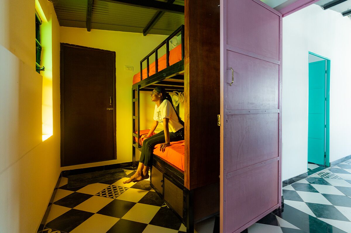 A room with a bunk bed, a door, and a checkered floor.