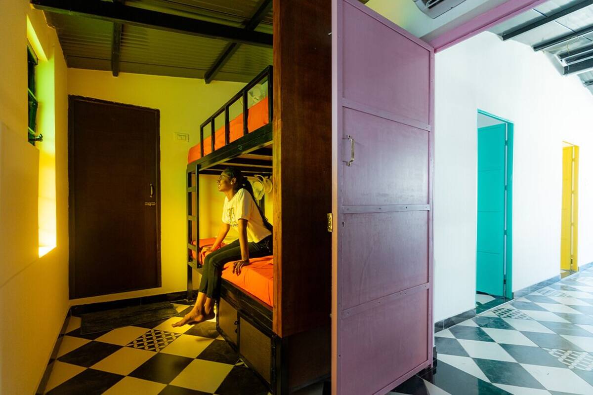 A dormitory room with bunk beds, a checkered floor, and a purple cabinet.