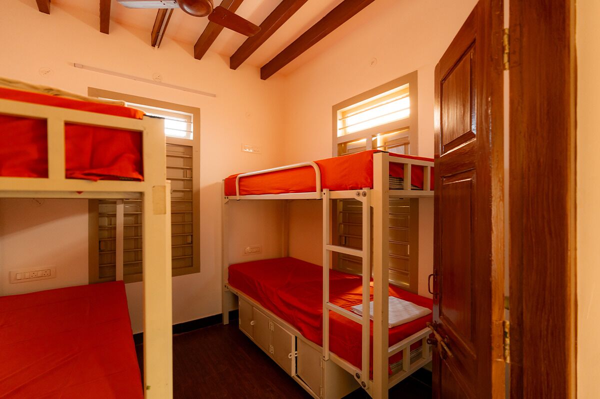 Un dormitorio con literas, vigas de madera en el techo y una puerta.