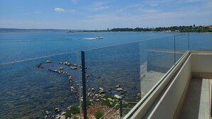 A balcony with a clear view of a calm body of water, a distant shoreline, and a clear sky. - Plava Laguna - Direkt am Strand und mit Meerblick (Seline)