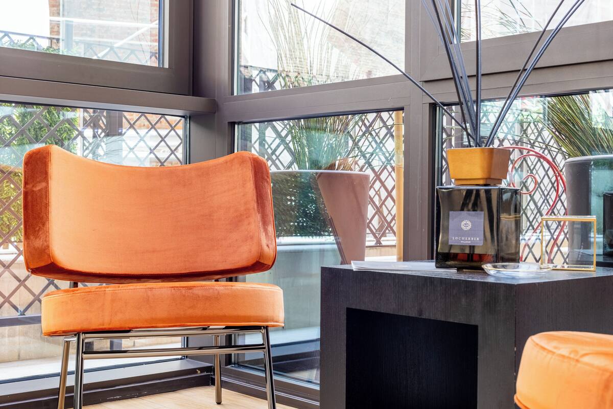 Ein modernes Interieur mit einem großen Fenster, einem schwarzen Schreibtisch und einem orangefarbenen Stuhl.