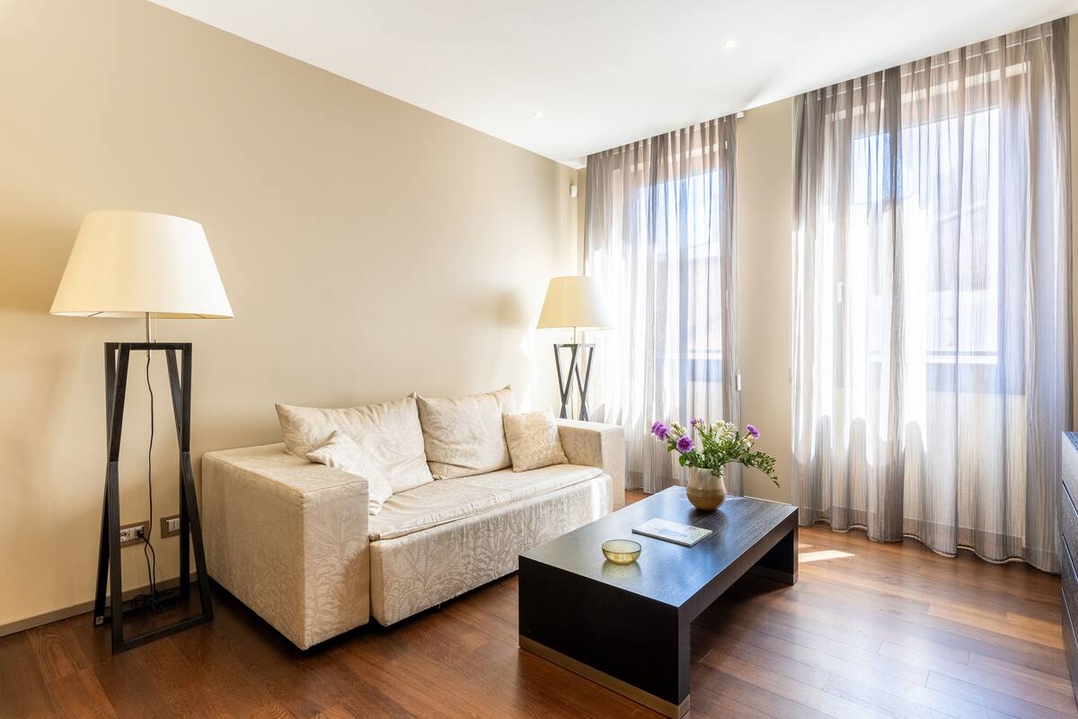 Ein modernes Wohnzimmer mit einer Couch, einem Couchtisch und zwei Stehlampen.
