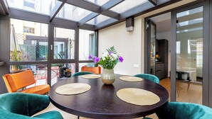 Un espace repas moderne avec une table ronde, des chaises vertes et un vase de fleurs.