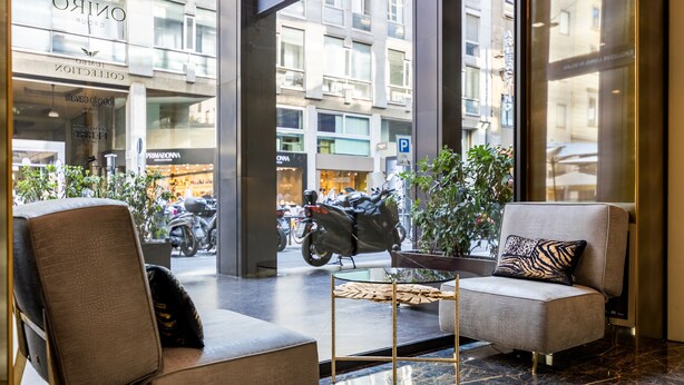 Un hall d’entrée moderne avec deux canapés, une table basse en verre et une vue sur la rue.