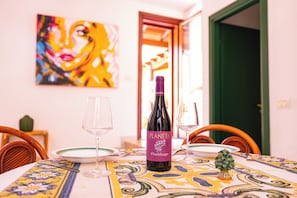 A dining table with a bottle of Planeta Plumbago wine, two wine glasses, and a small potted plant.