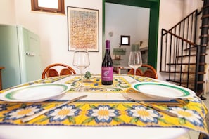 A dining table set with plates, cutlery, and a bottle of wine. - DURING HOME - Beach Apartment with Patio & Free Parking (Castelvetrano)