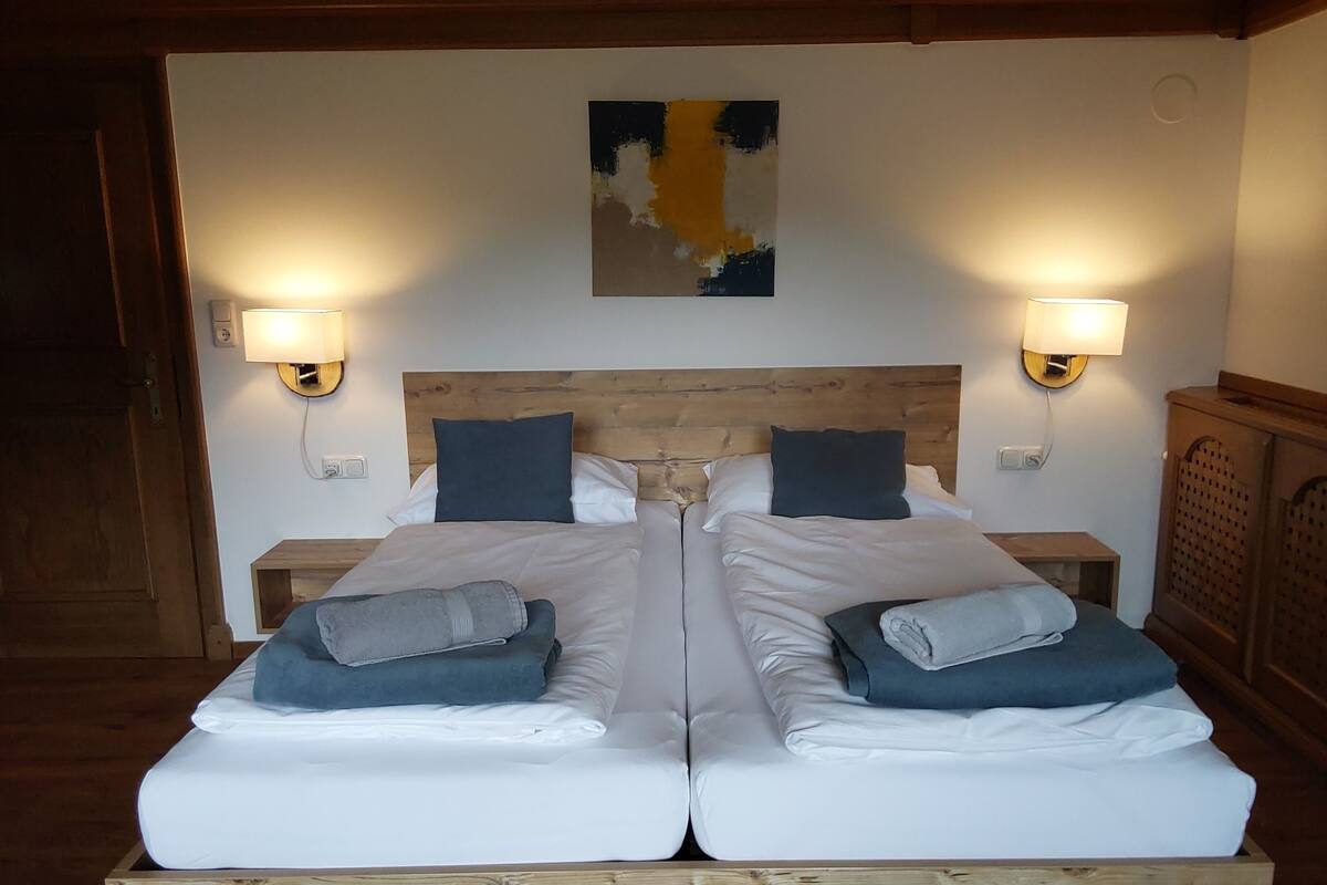 A double bed with white linens, two bedside tables with lamps, and a wooden headboard.