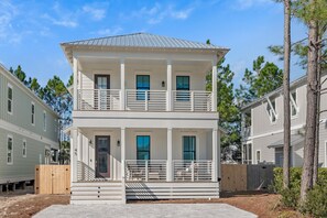 A two-story house with a balcony, a front porch, and a fenced yard. - New Seagrove Home - Steps to Beach, Bikes, Pool (Seagrove Beach)