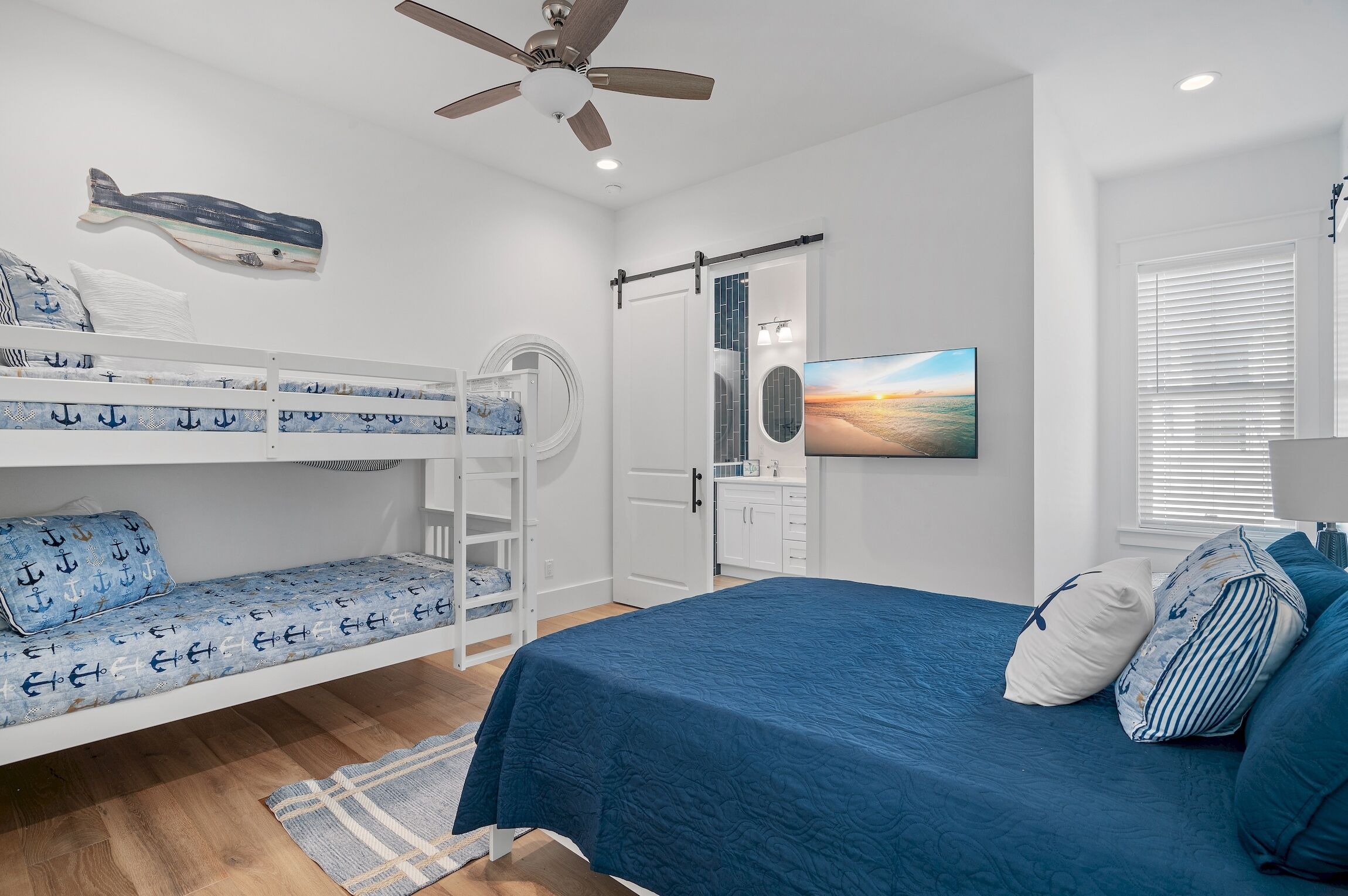 A bedroom with bunk beds, a ceiling fan, a TV, and a window with blinds.