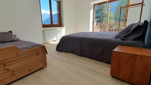 A bedroom with two wooden beds, a radiator, and a window with a view of mountains.