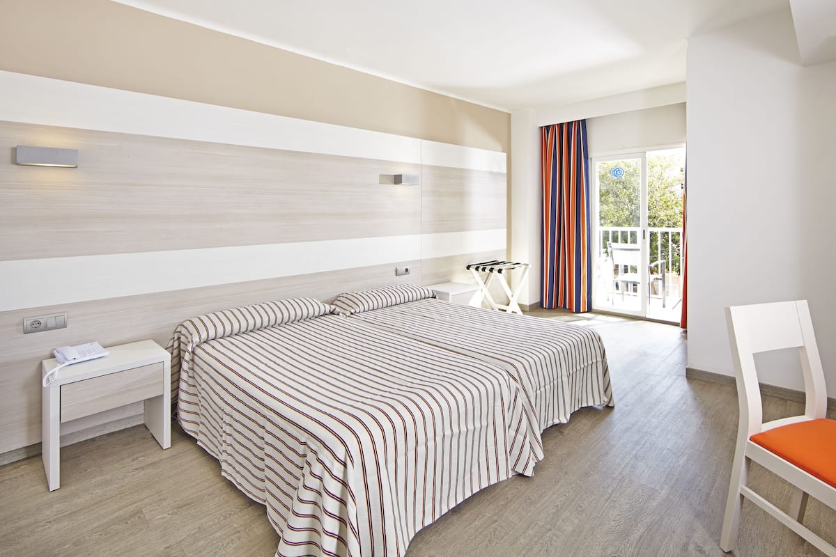 Moderni hotellihuone, jossa on suuri sänky, yöpöytä, tuoli ja näkymä ulos.