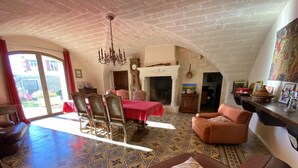 A spacious living area with a dining table, leather sofas, patterned floor tiles, and a fireplace. - Le Mas de la Coquille (Castries)