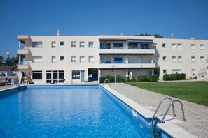 A modern building with a swimming pool, balconies, and a well-maintained lawn. - Tranquilidad, Naturaleza y Mar. Tu Refugio (L'Eucaliptus)