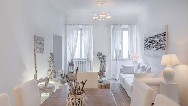 A modern living room with a wooden dining table, white sofas, and a chandelier. - Frattina 11 people (Rome)
