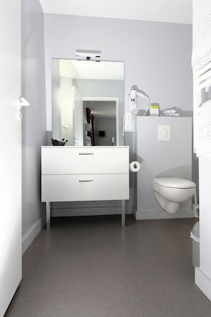 Une salle de bain moderne avec un meuble-lavabo blanc, des toilettes et un miroir.