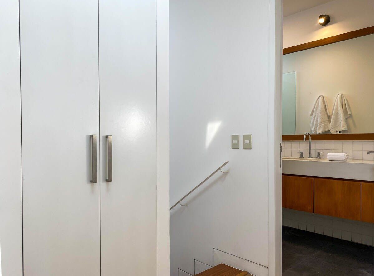 A modern bathroom with a white vanity, wooden cabinets, and a glass shower enclosure.