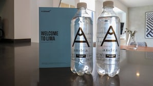 Two water bottles labeled 'andea' on a counter with a 'WELCOME TO LIMA' sign in the background.