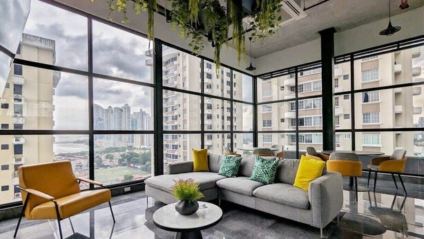A modern living room with a gray sofa, yellow and green pillows, a small round table with a plant, and a yellow armchair. - w* | Refined 1BR in San Francisco (Panamá)