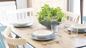 A dining table set with plates, cutlery, and a centerpiece of green plants in a ceramic bowl. - APARTAMENTOS CREATIVOS VILLARUBEI (Villarroya de los Pinares)