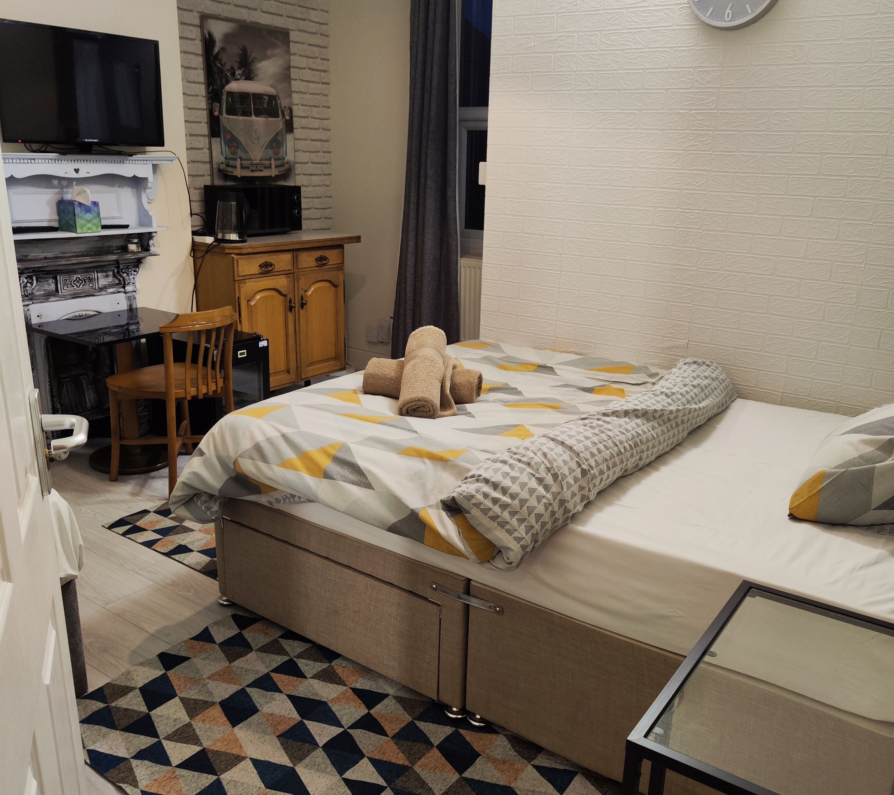 Habitación de hotel con cama, escritorio, silla, televisión y un adorno en la pared.