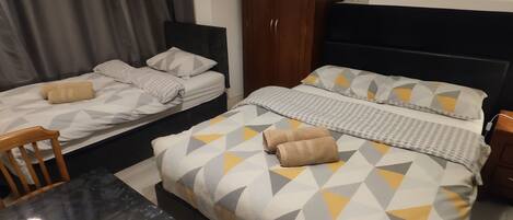 Una habitación de hotel con dos camas, una mesa de comedor y un armario de madera.