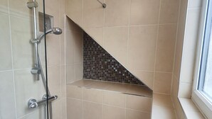 A shower with a glass door, a tiled shower area, and a small window. - St Lucia guest house (Leicester)