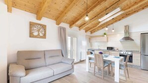 Un salon moderne comprenant un canapé, une table à manger avec des chaises et un coin cuisine avec une cuisinière et un réfrigérateur.