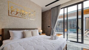 A hotel room with a large bed, a headboard, a nightstand with a lamp, and a view of the outside through a sliding glass door. - Fishermen Pool Villa Samui (Chang Wat Surat Thani)